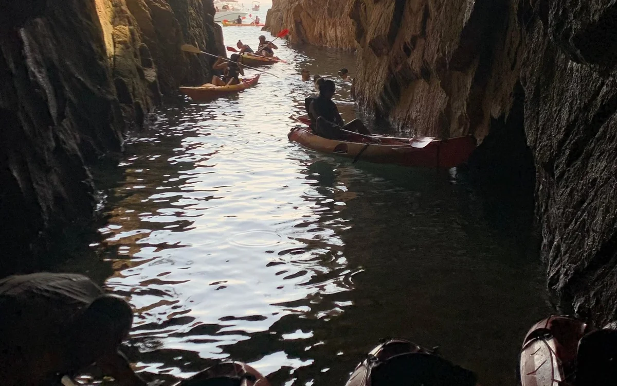 Kayaks floating inside a narrow rock channel where the daylight stops
