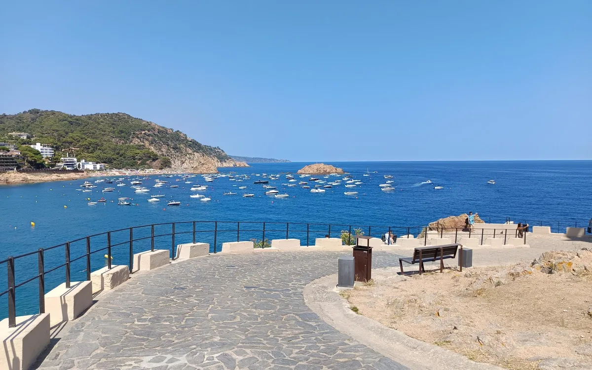 A rocky headland with a railed viewpoint above clear turquoise water
