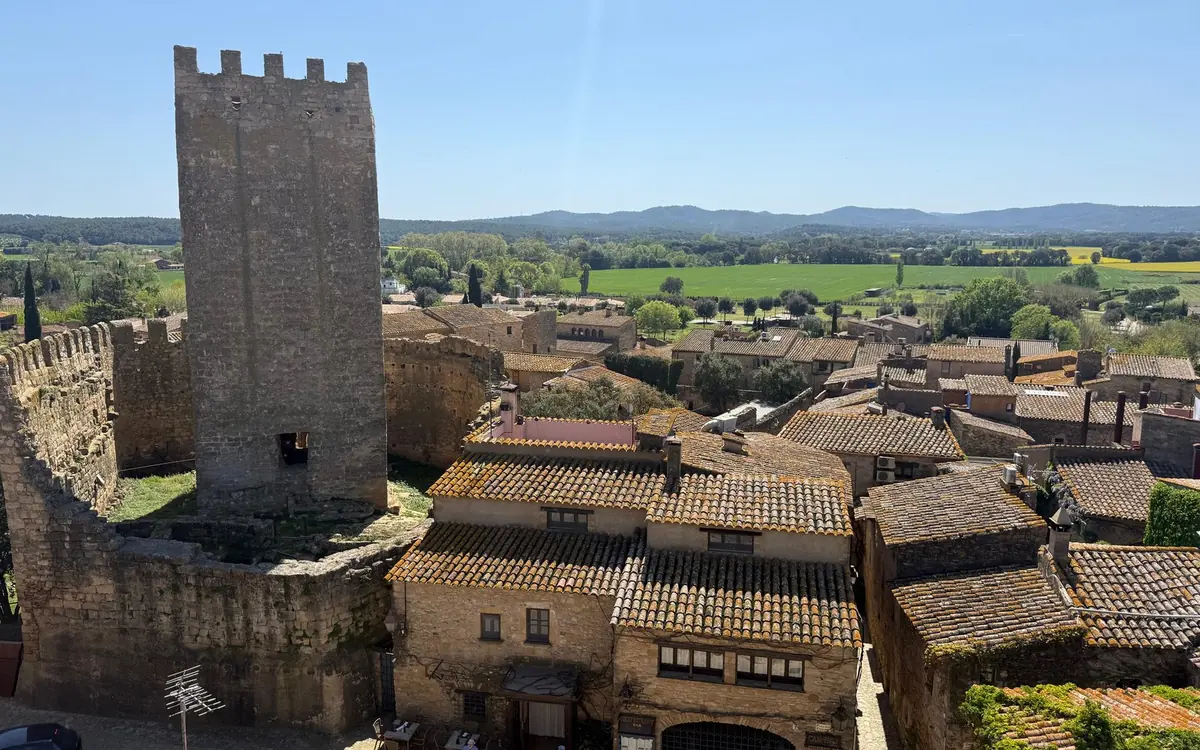 A square stone tower above tiled village roofs with fields behind