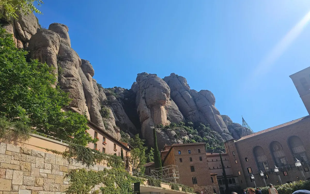 Bare rounded rock towers rising above the monastery roofs and trees