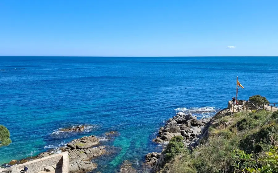 A railed viewpoint on the rocks above deep blue sea