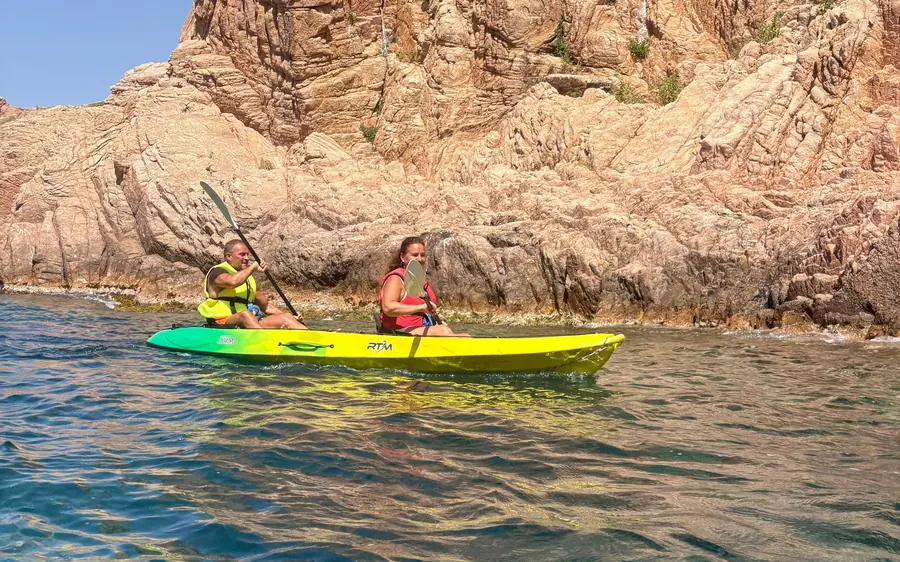 Two paddlers in a yellow kayak on open blue water