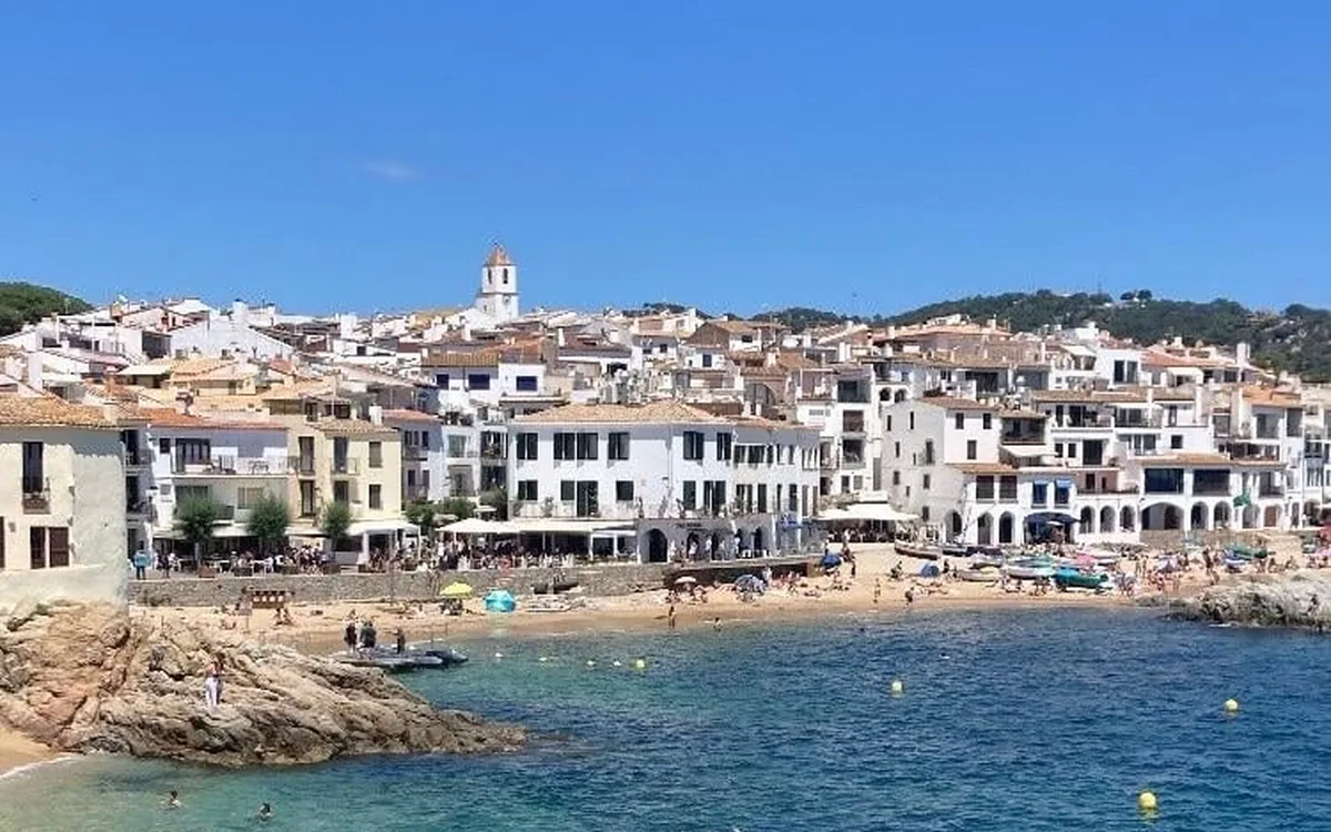 White houses stacked above a small beach and clear shallow water